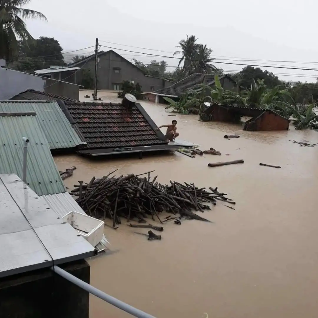 Người dân ngồi trên nóc nhà chờ lực lượng tới giải cứu. Ảnh: Báo Bình Định